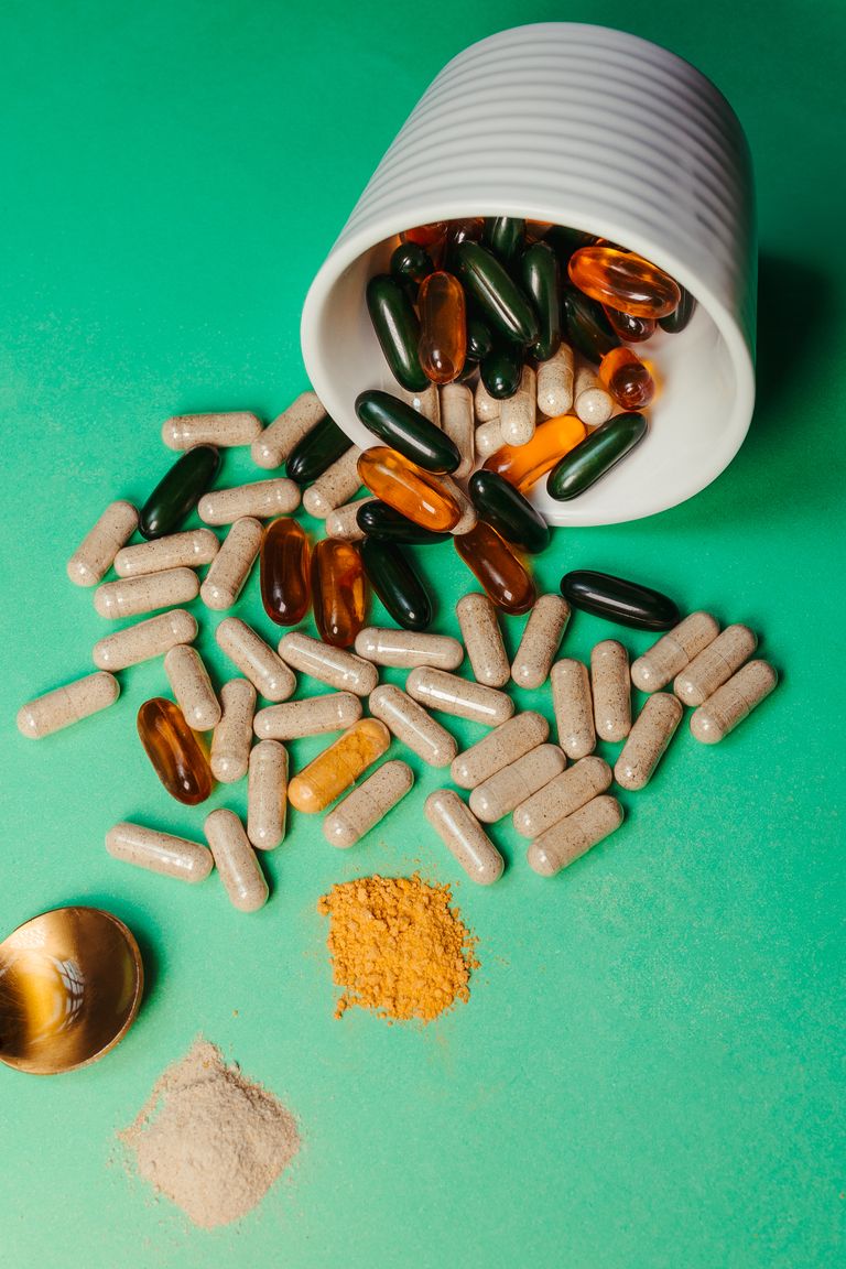 A vibrant arrangement of capsules spilling from a cup onto a green backdrop.