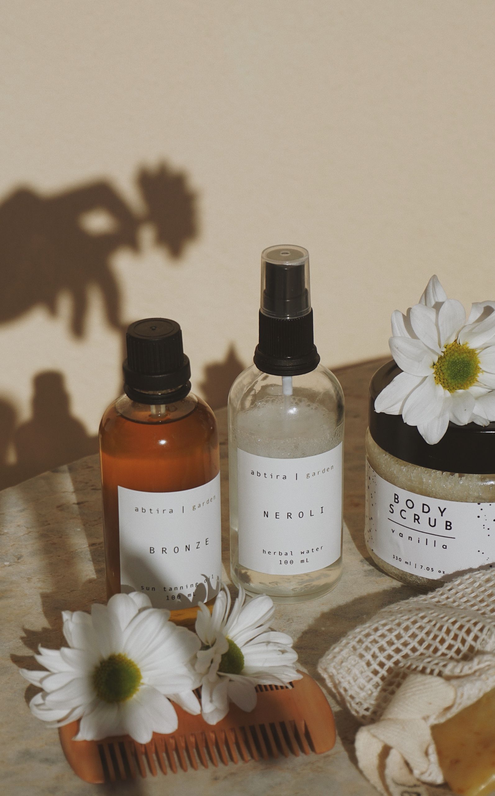 Aesthetic arrangement of body care products with daisies, sunlight, and shadows.
