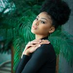 Stylish woman with natural curly hair in a lush indoor setting.